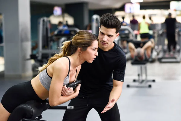 Personal trainer ajudando jovem mulher levantar pesos — Fotografia de Stock