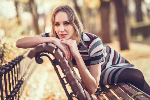 Jonge blonde vrouw zittend op een bankje van een park — Stockfoto