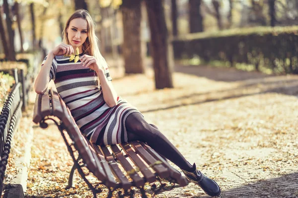 Молодая блондинка, сидящая на скамейке в парке — стоковое фото