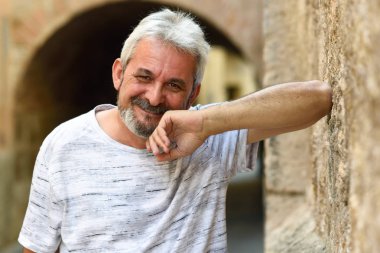 Olgun adam kamera kentsel arka planda bakarak gülen