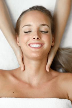Genç bir kadın spa merkezinde kafa masajı yaptırıyor..