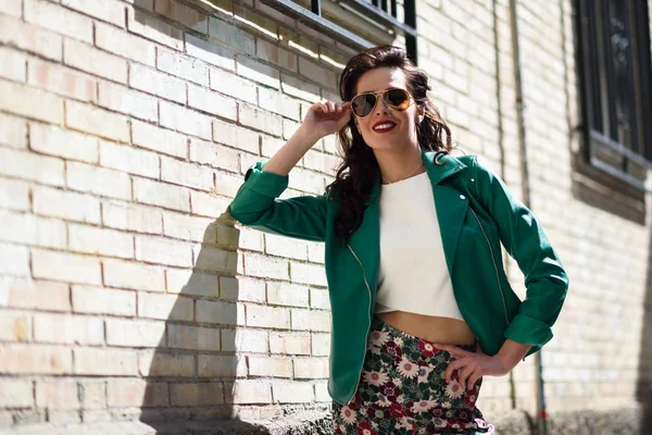 Mujer morena joven con gafas de sol en el fondo urbano —  Fotos de Stock