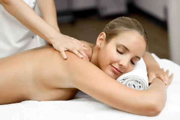 Jovem loira fazendo massagem e sorrindo no spa — Fotografia de Stock