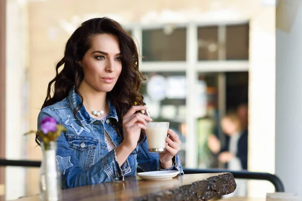 Woman sitting indoor in urban cafe wearing casual clothes