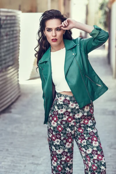 Kentsel arka planda gülümseyen genç esmer kadın.