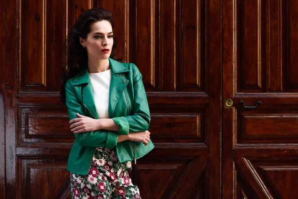 Kentsel arka planda gülümseyen genç esmer kadın.