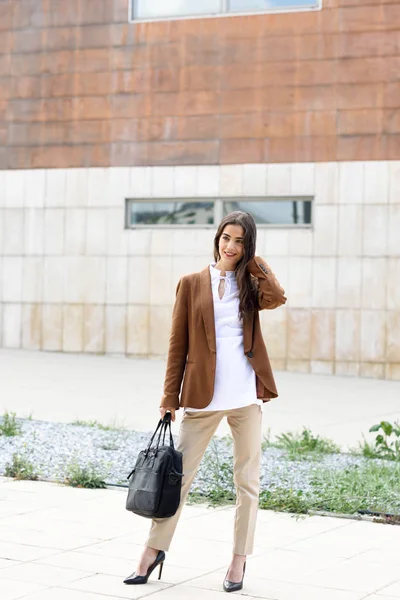 Ung affärskvinna stående utanför kontorsbyggnad med bri — Stockfoto
