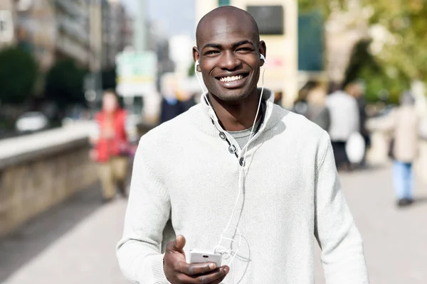 Czarny człowiek młody ze smartfonem w ręku w miejskich zadumany — Zdjęcie stockowe