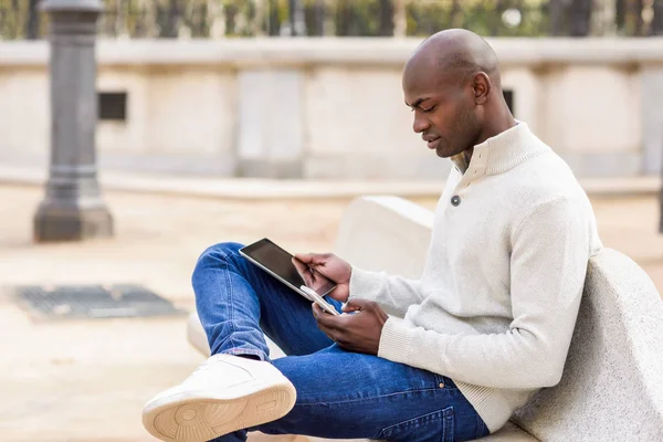 Schwarzer junger Mann blickt auf Tablet-Computer und Smartphone — Stockfoto
