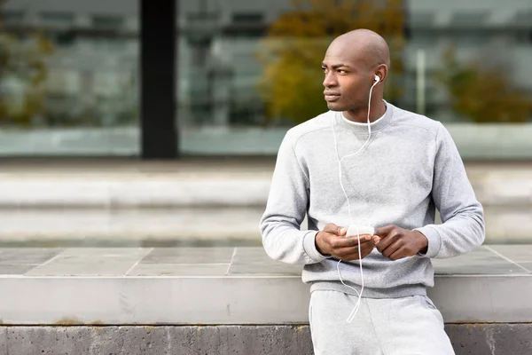 Atraktivní černý muž poslouchá hudbu se sluchátky v městských — Stock fotografie