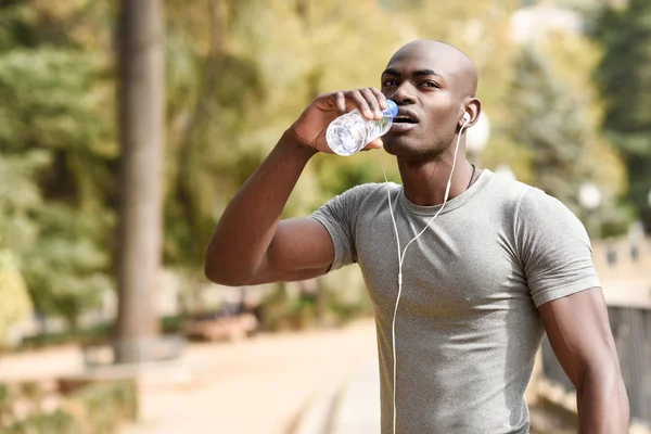Junger schwarzer Mann trinkt Wasser, bevor er in urbaner Umgebung läuft — Stockfoto