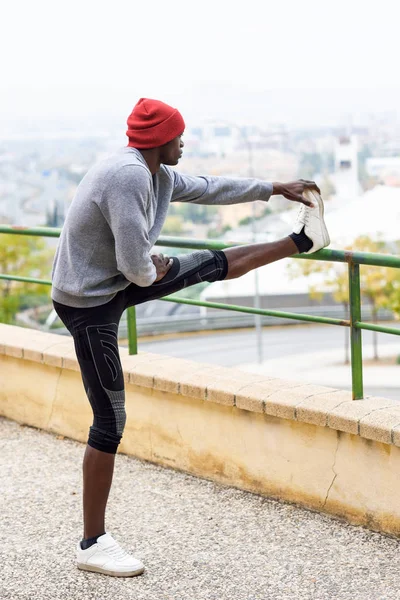 Schwarzer macht Stretching, bevor er im städtischen Hintergrund läuft — Stockfoto