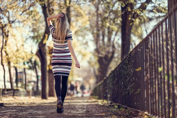 Jeune femme blonde marchant dans la rue — Photo