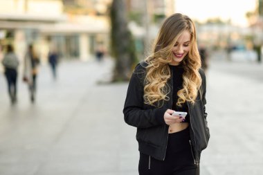 Sarışın kadın manifatura ile onun smartphone kentsel arka planda