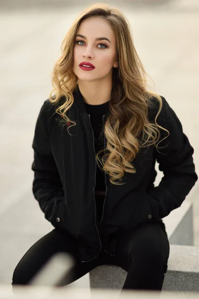 거리에 앉아 검은 자 켓을 입고 아름 다운 소녀. — 스톡 사진