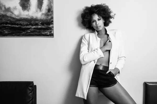 Young black woman afro hairstyle possing near a white wall