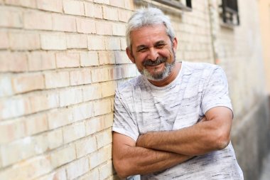 Olgun adam kamera kentsel arka planda bakarak gülen