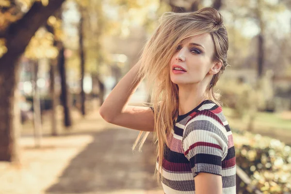 Jeune femme blonde debout dans la rue bougeant ses cheveux — Photo