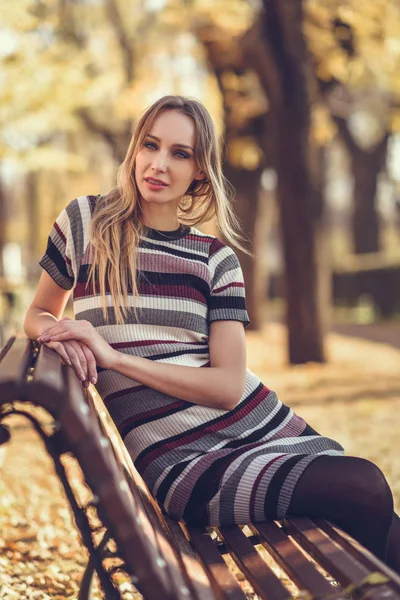 Giovane donna bionda seduta su una panchina di un parco — Foto Stock