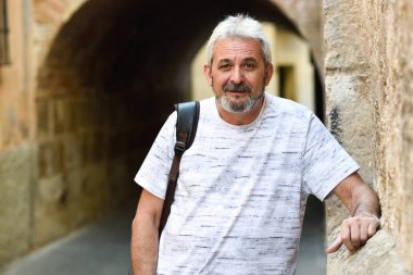 Olgun adam kamera kentsel arka planda bakarak gülen