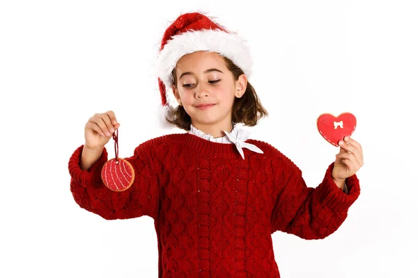 Αξιολάτρευτο κοριτσάκι που φοράει το καπέλο santa με χριστουγεννιάτικα μπισκότα — Φωτογραφία Αρχείου
