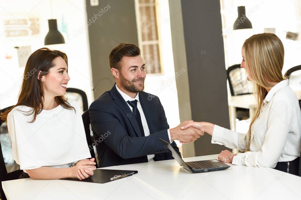 Smiling young couple shaking hands with an insurance agent