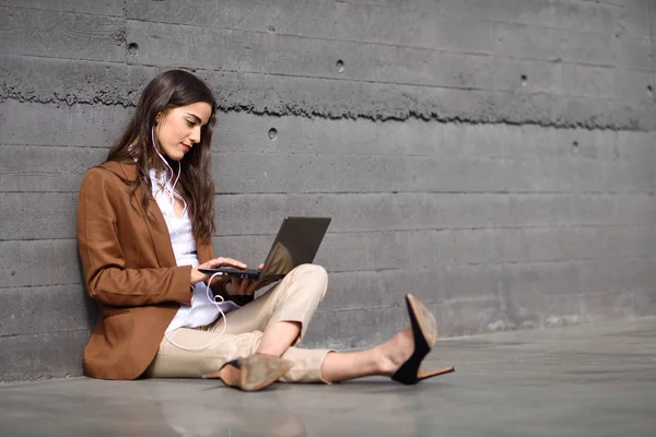 Młoda kobieta siedzi na podłodze patrząc na jej laptopie compu — Zdjęcie stockowe