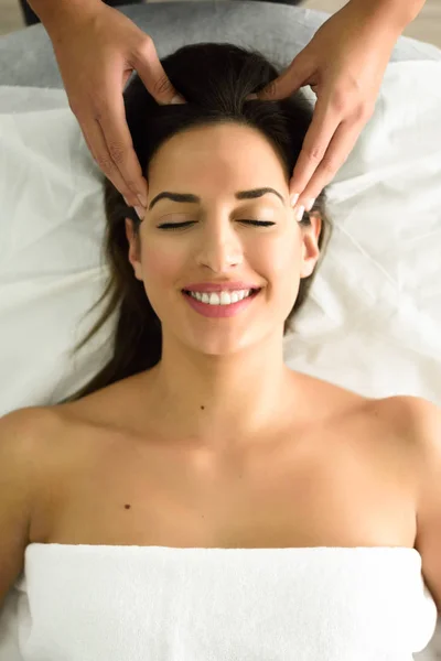 Joven mujer sonriente recibiendo un masaje en la cabeza en un centro de spa . — Foto de Stock