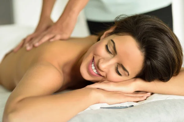 Jovem mulher recebendo uma relaxante massagem nas costas em um centro de spa . — Fotografia de Stock