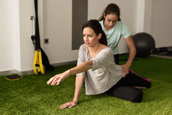 Fisioterapeuta asistiendo a mujer joven caucásica con ejercicio — Foto de Stock