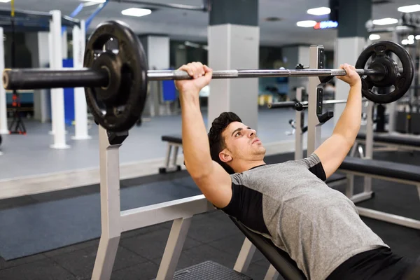 Homem jovem fisiculturista fazendo levantamento de peso no ginásio . — Fotografia de Stock