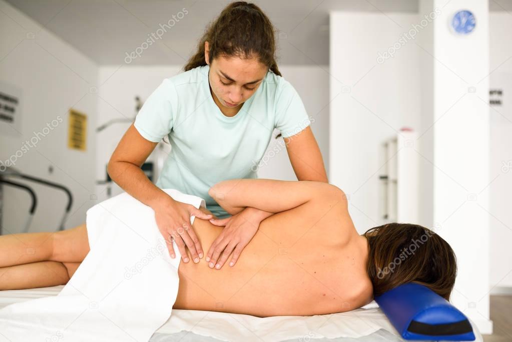 Professional female physiotherapist giving lumbar shoulder massa