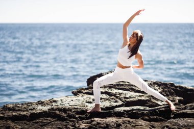 Genç kadın beyaz elbise giyen Beach yoga yaparken