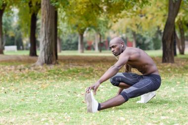 Kentsel arka planda çalıştırmadan önce germe yapan siyah erkek
