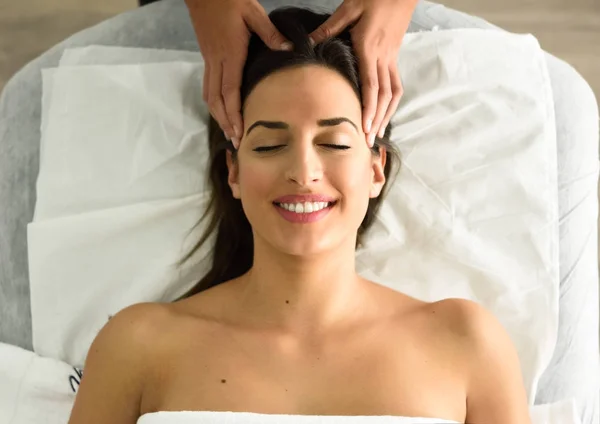 Joven mujer sonriente recibiendo un masaje en la cabeza en un centro de spa . — Foto de Stock