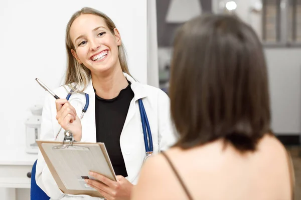 Vrouwelijke arts diagnose uit te leggen aan haar jonge vrouw patiënt. — Stockfoto