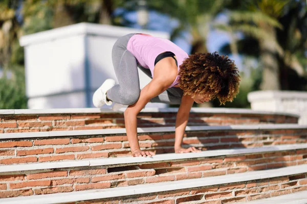 Чорна підтягнута жінка робить фітнес-акробатику на міському фоні — стокове фото