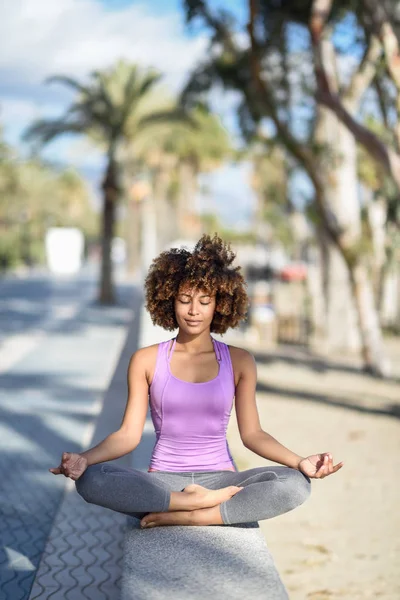 Black woman, afro hairstyle, in lotus pose with eyes closed in t — Stock Photo, Image