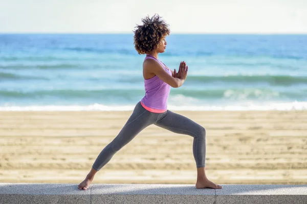Mujer negra, peinado afro, haciendo yoga en la guerrera asana en la — Foto de Stock