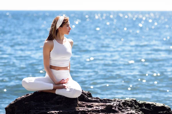 Mujer joven haciendo yoga en la playa vistiendo ropa blanca —  Fotos de Stock