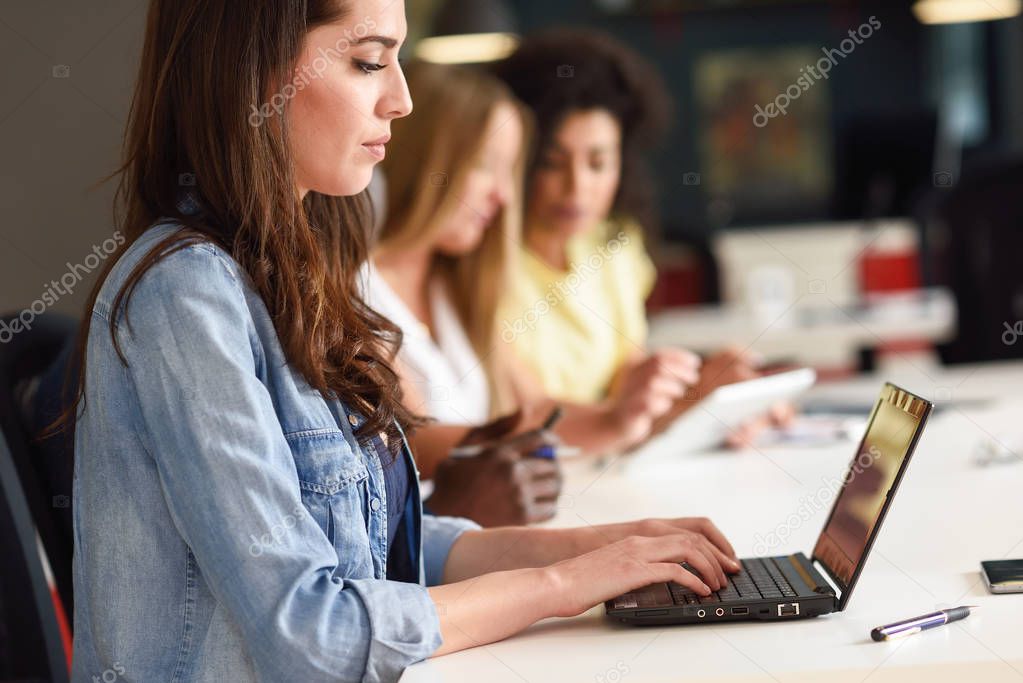 Young woman studying with laptop computer on white desk. 