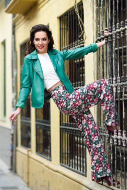 Kentsel arka planda gülümseyen genç esmer kadın.