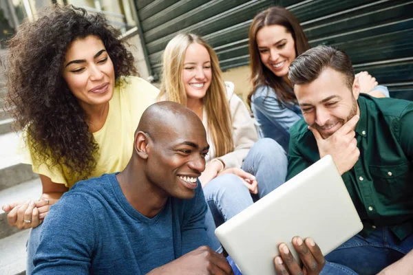 Gruppo multietnico di giovani che guardano un tablet — Foto Stock