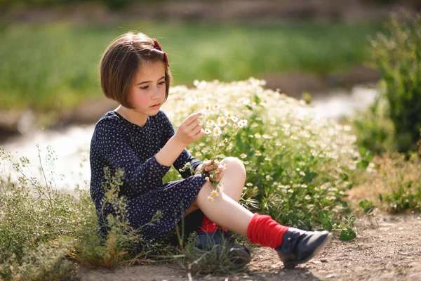 Kleines Mädchen sitzt in der Natur Feld trägt schönes Kleid — Stockfoto