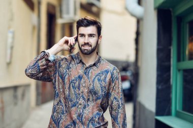 Onun smartphone ile konuşurken rahat kıyafetler giyen genç adam 