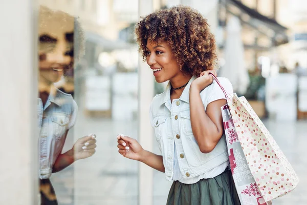 Jonge zwarte vrouw, afro kapsel, kijken naar een etalage — Stockfoto