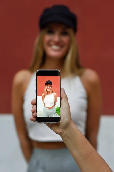 Женщина фотографирует смартфоном своего друга — стоковое фото