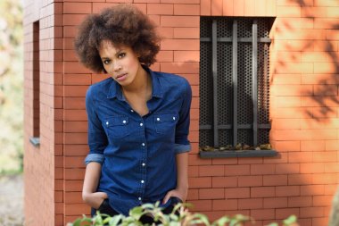 Young black woman with afro hairstyle standing in urban backgrou clipart