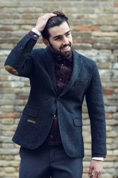 Joven barbudo sonriendo en el fondo urbano vistiendo el británico — Foto de Stock