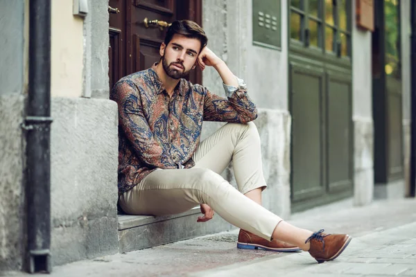 Giovane uomo barbuto, modello di moda, seduto in un passo urbano noi — Foto Stock